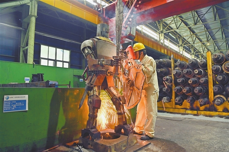 在方大特钢轧钢厂优特钢钳工班，电焊工尹剑为钢铁机器人进行补焊作业。