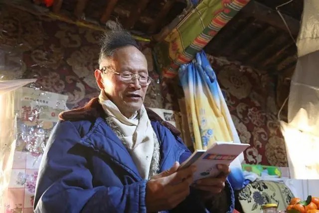 ▲王万青在家中阅读书籍　新华社记者　马莎　摄