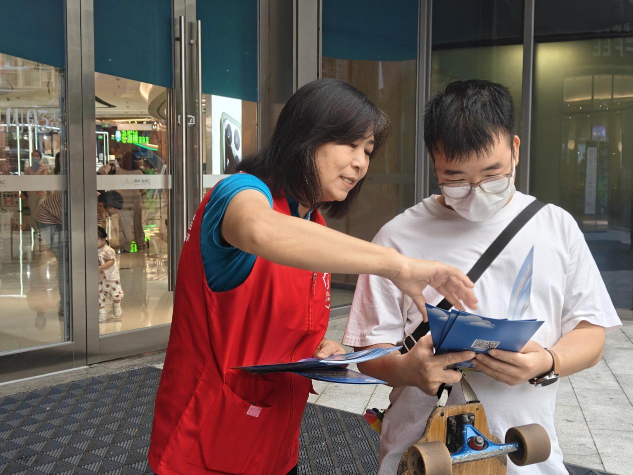 志愿者向居民宣传惠民政策，拍摄人：张小情