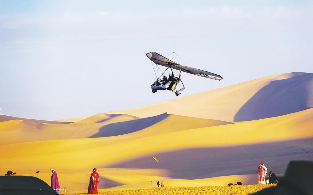 时下，敦煌市进入最佳秋景观赏季节，游客乘坐滑翔机空中俯瞰大漠美景。鸣沙山的沙丘在秋日的阳光下闪耀着金色的光芒，连绵起伏的线条犹如大自然用神奇画笔勾勒出的雄浑画卷。新甘肃&middot;甘肃经济日报通讯员　王斌银　摄