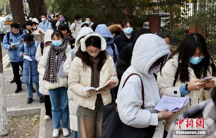 资料图：北京第十二中学校本部考点外，考生在入场前复习。当日，中央机关及其直属机构2024年度考试录用公务员公共科目笔试举行。中新社记者 易海菲 摄