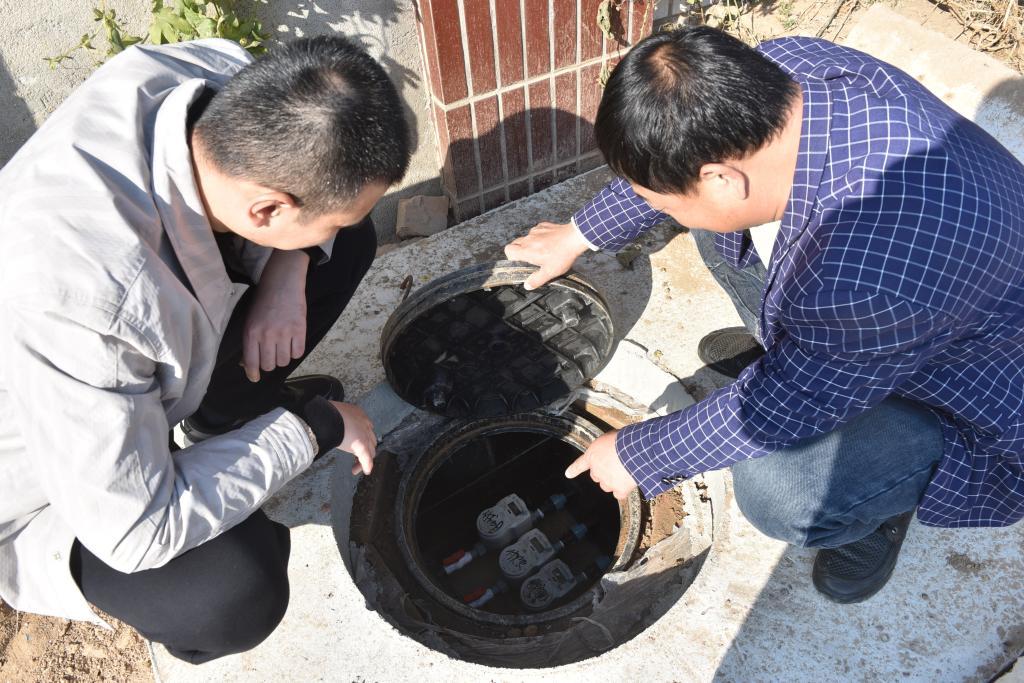 苦水营村党支部书记付铁军(右一)向乡镇包村干部介绍村里新安装的智能水表。（受访者供图）