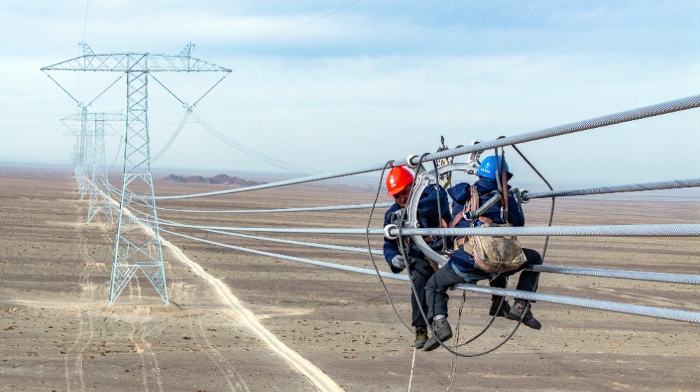 ▲近日,施工人员在哈密-重庆±800千伏特高压直流输电线路工程(新疆段)安装间隔棒。通讯员 马元 摄