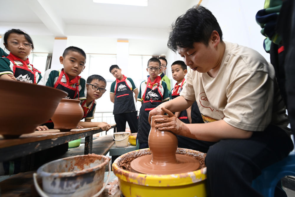 在临洮县马家窑彩陶文化小镇，陶艺师为临洮县西街小学陶艺社团的学生演示陶坯制作。新华社记者　范培珅　摄