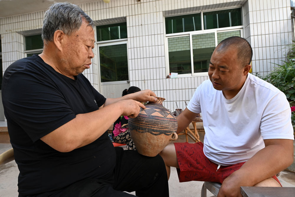 阎建林（左）在家中与儿子闫小虎探讨彩陶的线条　新华社记者　范培珅　摄