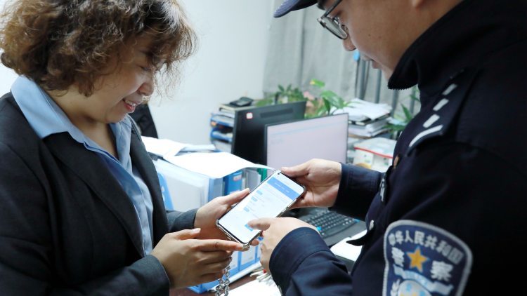 民警指导沈女士用手机申领居住证