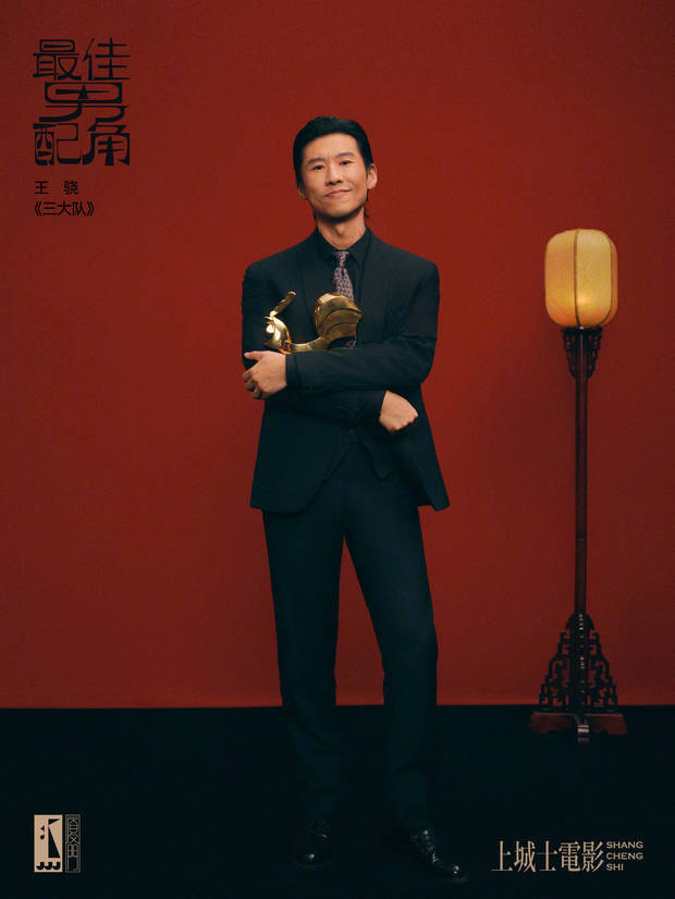 王骁拥抱金鸡奖杯，英气潇洒。