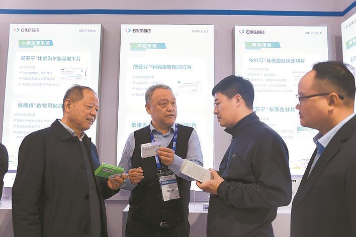 石家庄四药集团董事长苏学军（左二）在展台为到访的客户介绍产品。 本报记者 袁立朋 摄