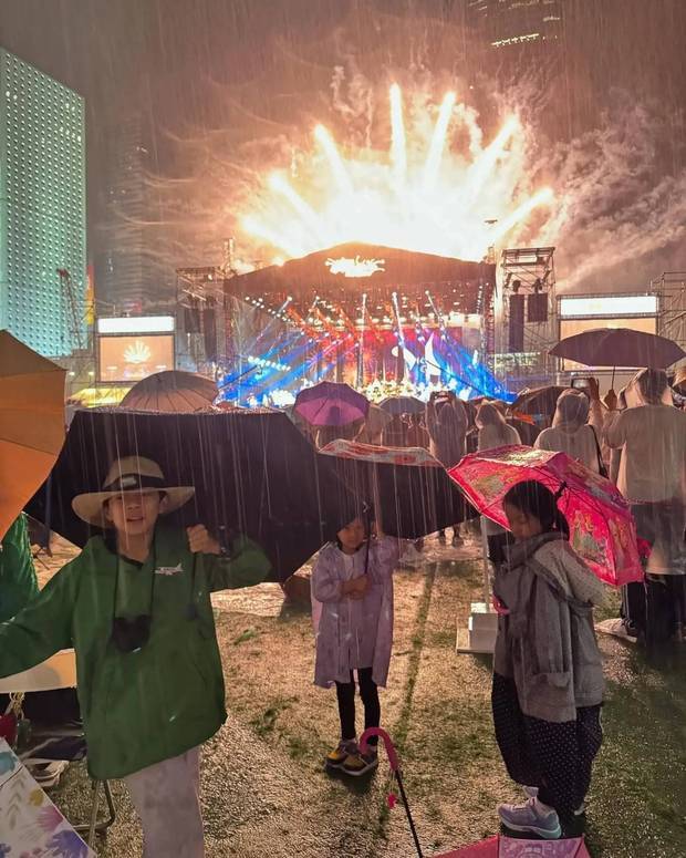 小朋友们撑着雨伞，与灯光秀合影。