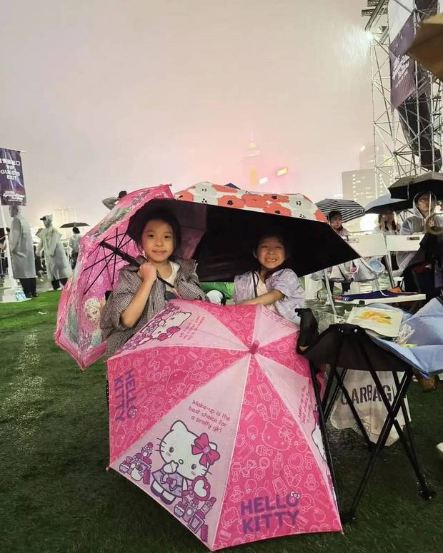 霍启刚女儿举着雨伞，笑容甜美。