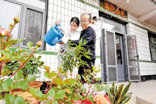 11月12日，景县后留名府乡苦水营村村民张汝连（右）带着外孙女在小院里侍弄花草。本报记者 焦 磊摄