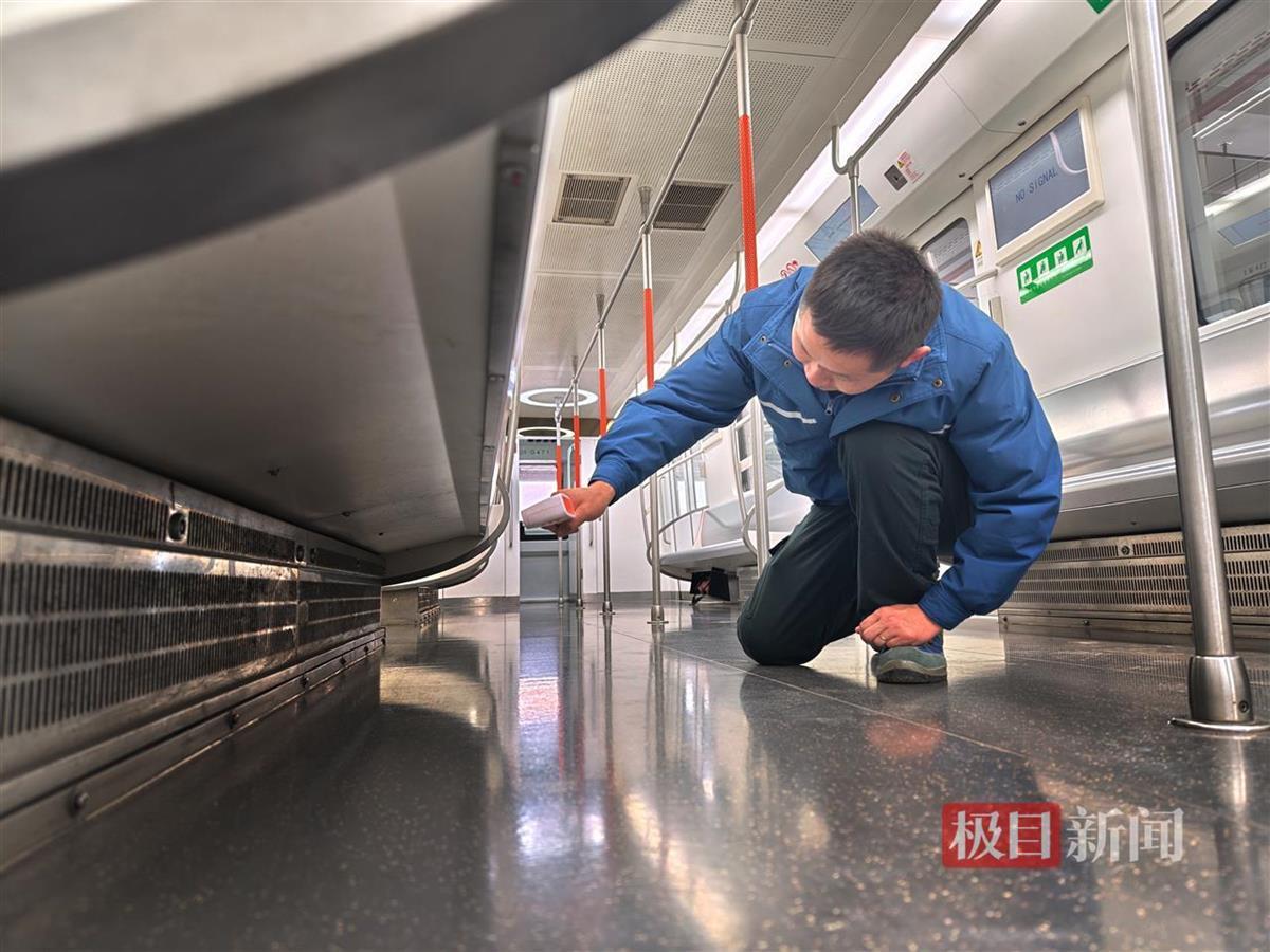 地铁列车检修人员通过点温枪确认座椅下方电暖工作状态