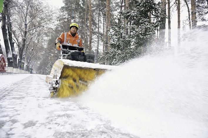 环卫工人使用手扶式清雪机清雪。