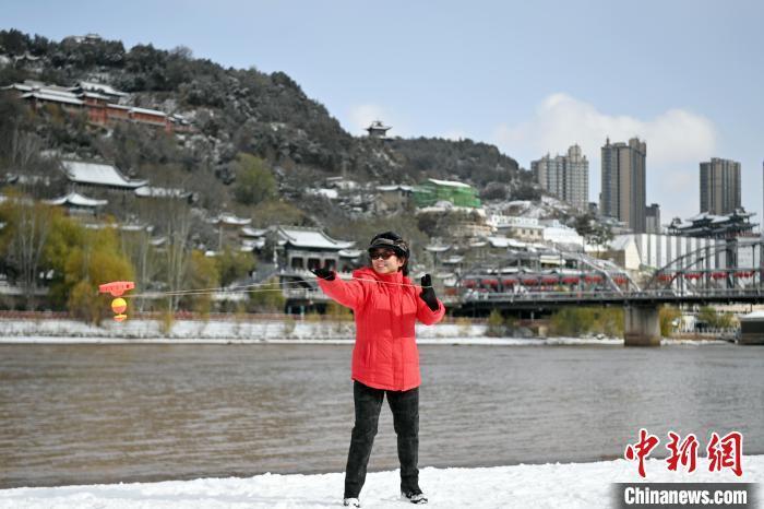11月25日，甘肃兰州迎来降雪天气。图为市民雪后在黄河边抖空竹。中新社记者　九美旦增　摄