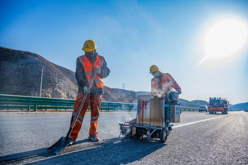 ▲工人们在给中通道公路上画交通指示线