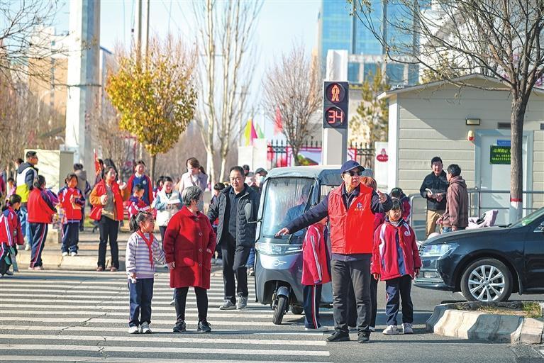 在兰州新区第九小学门口，交通志愿者引导学生安全过马路。本版图片除署名外均由兰州新区报记者　罗晋业　摄