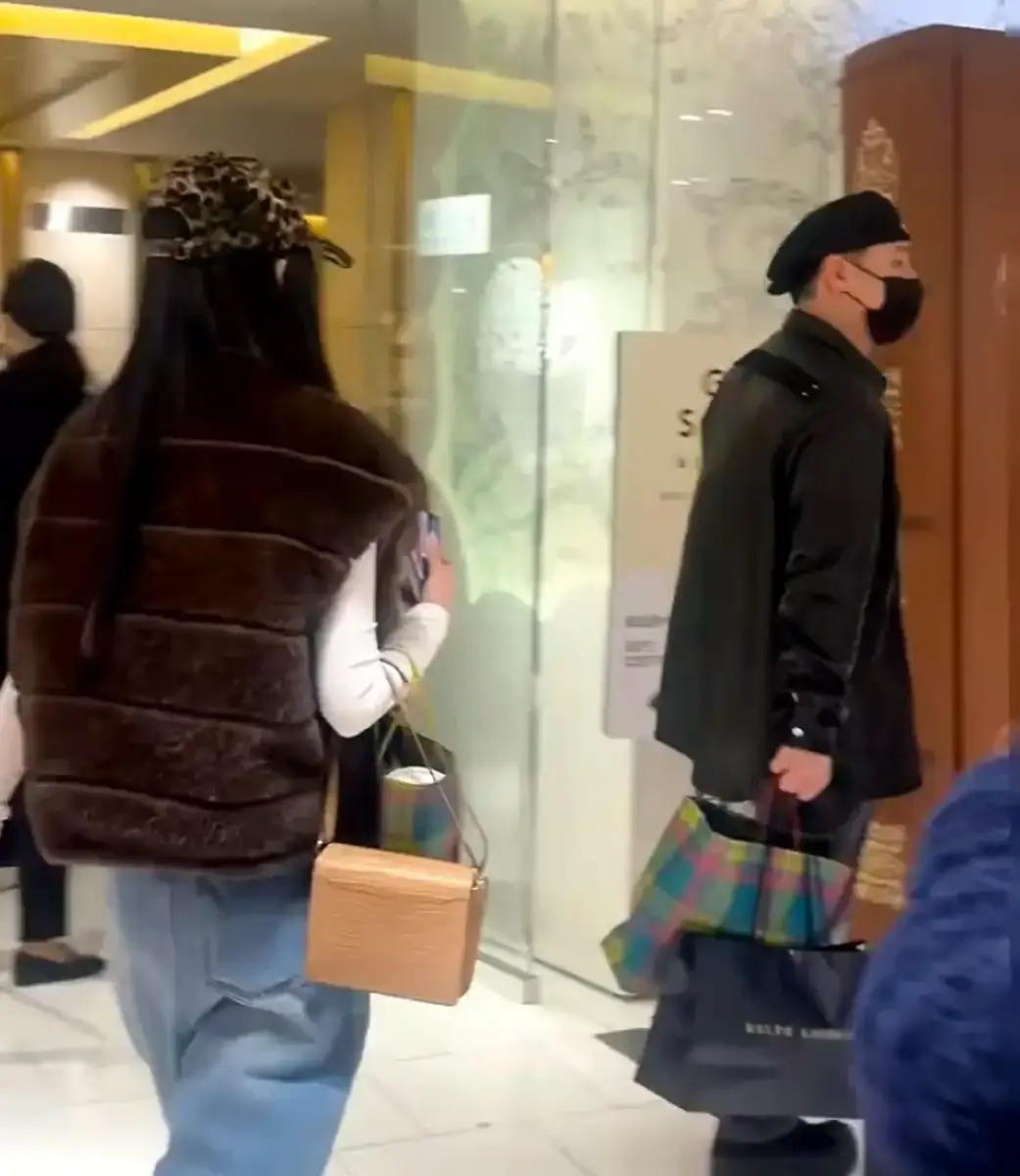 潘玮柏拎着袋子走在前面，妻子宣云跟在他身后。