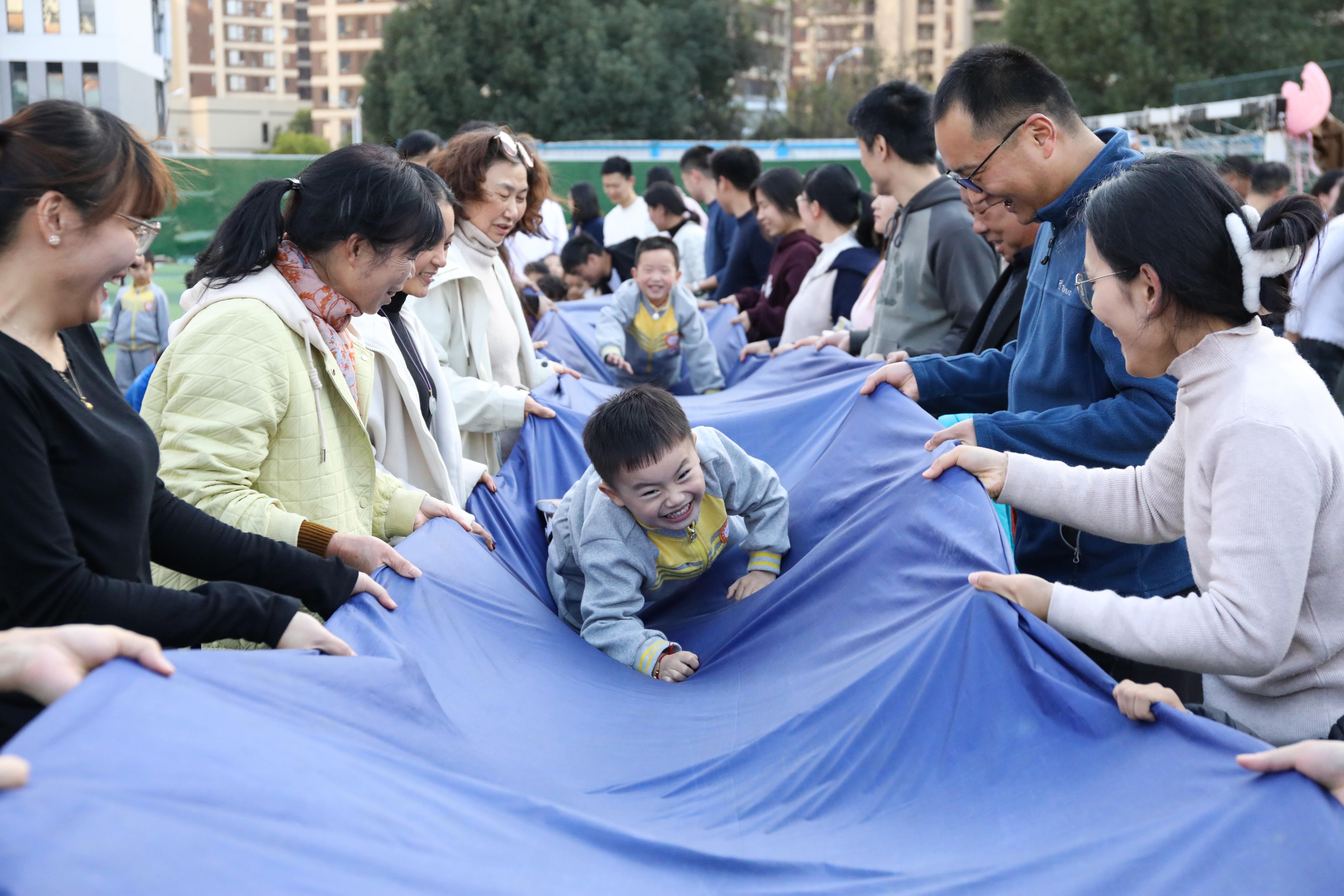 (2024年11月30日,家长与幼儿在亲子运动会上开展趣味运动游戏。 陈家乐 摄)
