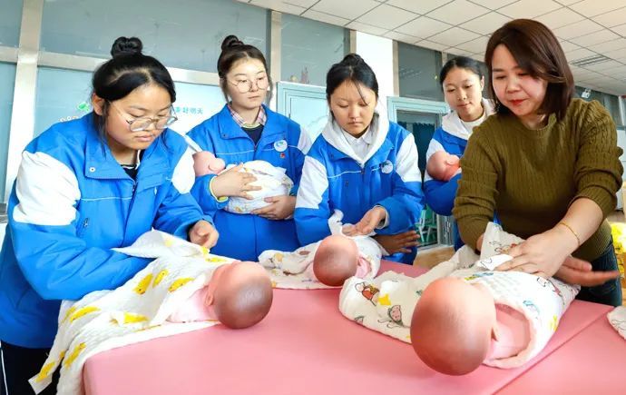 12月4日,张掖市高台县职业中专的实训楼婴幼儿保育专业实训室内,老师正在指导同学们进行婴幼儿护理要领的训练。