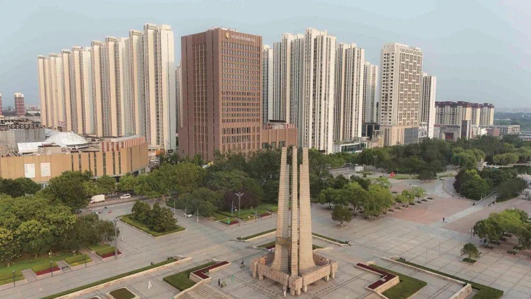 唐山抗震纪念碑广场周边高楼耸立，绿树成荫。