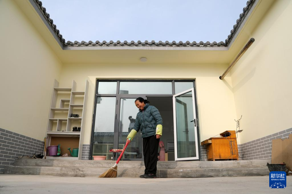 12月11日，在积石山县刘集乡团结村集中安置点，村民姬芳芳打扫自家小院。新华社记者　马莎　摄