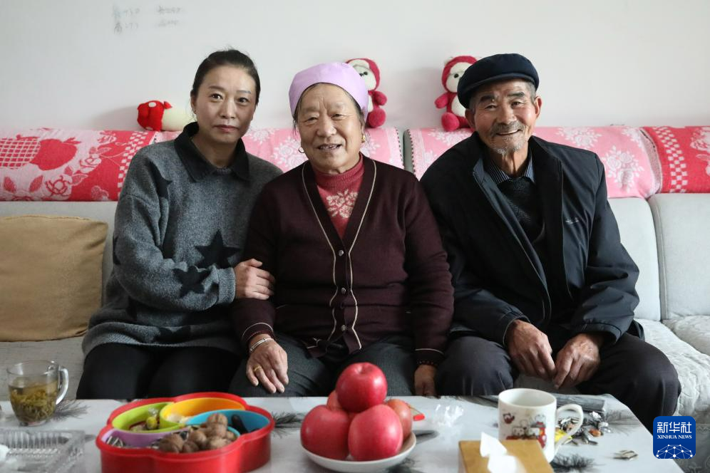 12月12日，在积石山县大河家镇康吊村集中安置点，村民宋永红（左）在新居与父母合影。新华社记者　马莎　摄