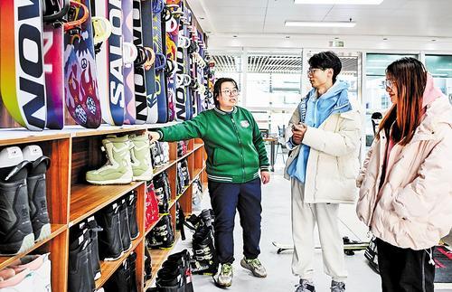 12月2日，游客在太子城高铁站外的雪具店选购商品。