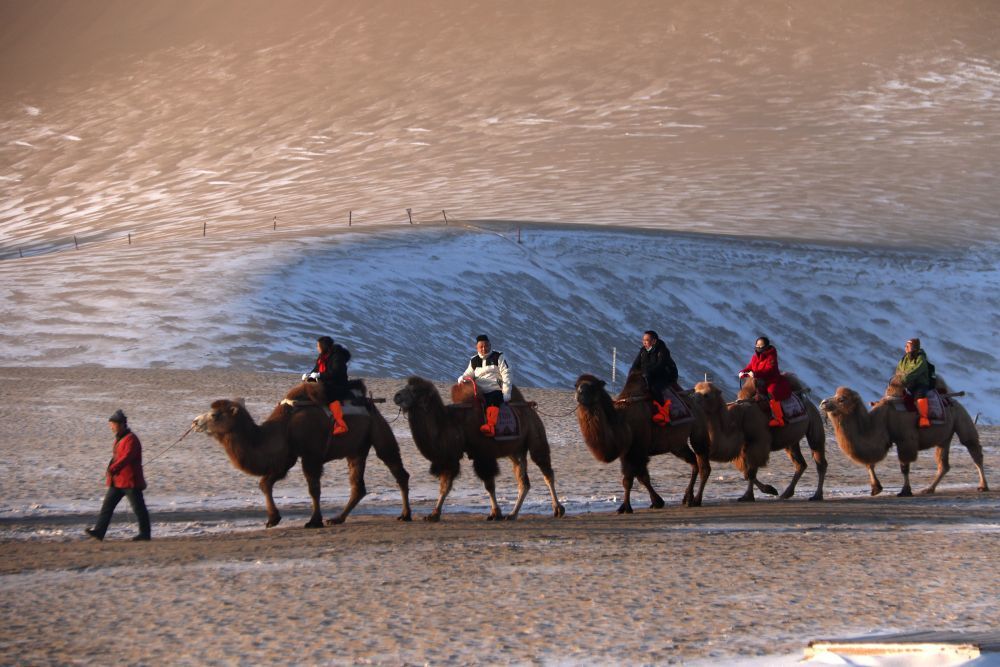 2024年12月12日，游客在甘肃省敦煌市鸣沙山月牙泉景区游览。张晓亮　摄