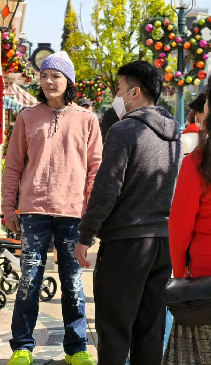 向佐头戴紫色帽子，搭配粉色上衣、牛仔裤以及荧光绿鞋子，着装相当鲜艳夺目。