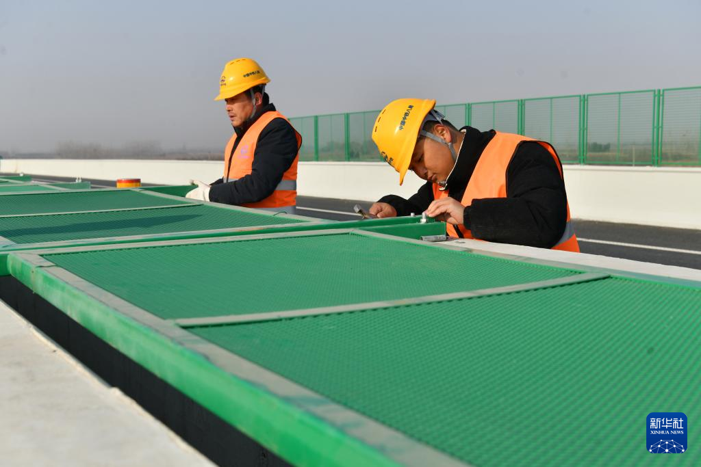 12月20日,中铁八局集团工人在曲港高速沧州段七标段工地安装护栏。