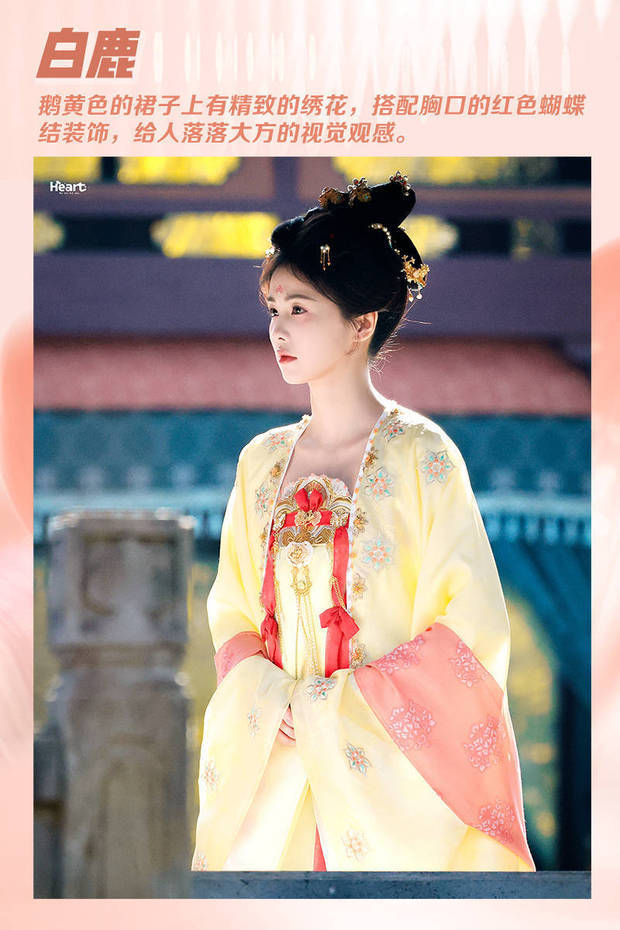 白鹿的黄色唐装上绣着精致的小花，胸口有红色的蝴蝶结作为点缀，头发上没有繁琐的装饰，而是选择了和衣服相匹配的简单发簪，给人温柔秀美的视觉观感。
