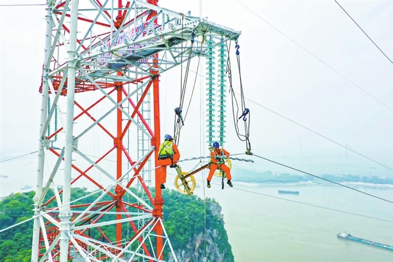 工人在棉船风电项目110千伏配套线路跨长江放线作业。（彭 琴 本报记者 欧阳海员 摄）