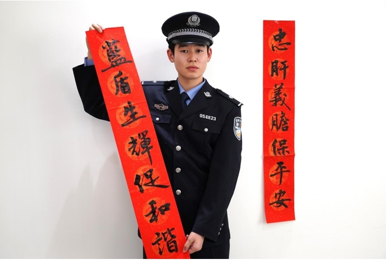 沧州市公安局新华分局刑警大队民警冯建腾展示对联内容：忠肝义胆保平安，蓝盾生辉促和谐。