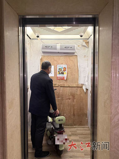 工作人员演示推电动自行车进电梯后、电梯会发出提示声并停运的情景。