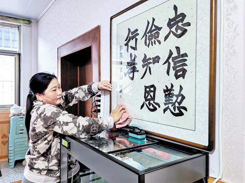 11月4日,村民张立平正在擦拭装有家训的镜框。 本报记者 陈宝云摄