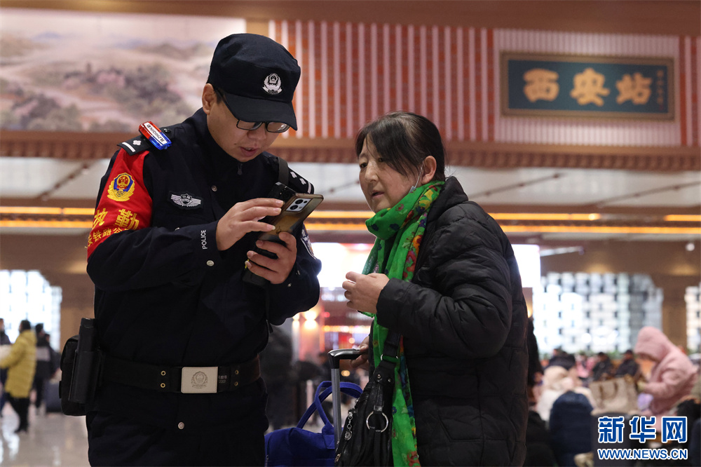 2025年1月1日，在西安火车站候车室里，坚守岗位的西安铁路民警帮助乘车旅客。张鑫摄