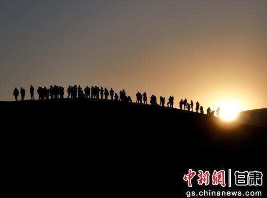 元旦早晨，一轮红日从甘肃省敦煌市鸣沙山新月泉景区真切渐渐起飞，旅客不雅赏大漠日出，欢度元旦假期。（张晓亮　杨盖）