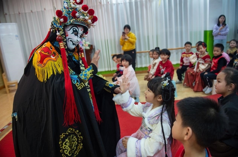 沧州市运河区第四幼儿园的小朋友与川剧变脸演员互动。