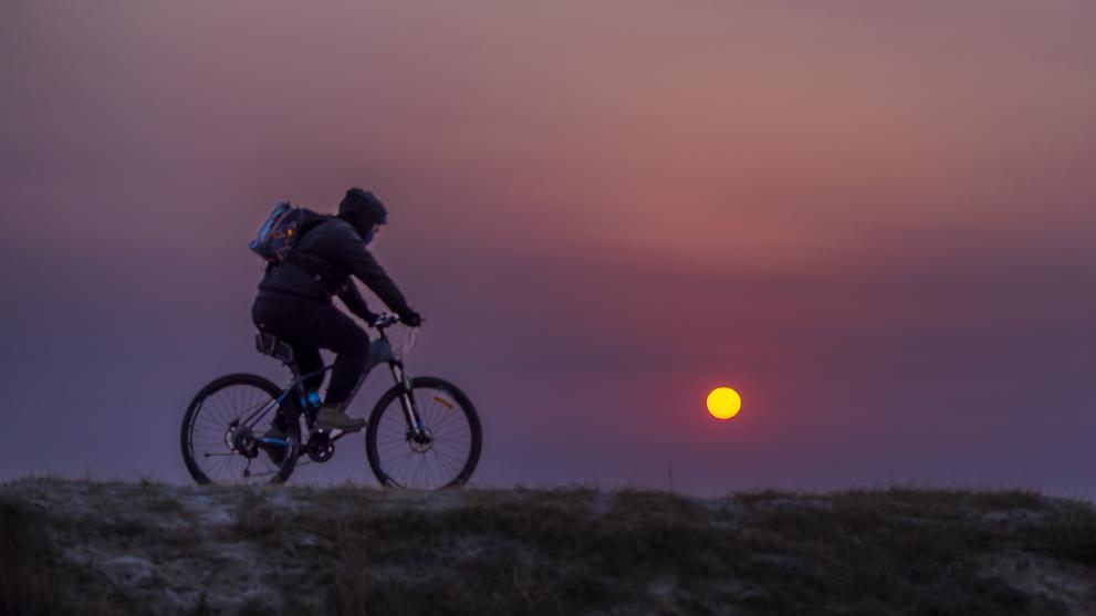 朝霞映照着身影，市民沿着海边悠然骑行。靳淑丽 摄