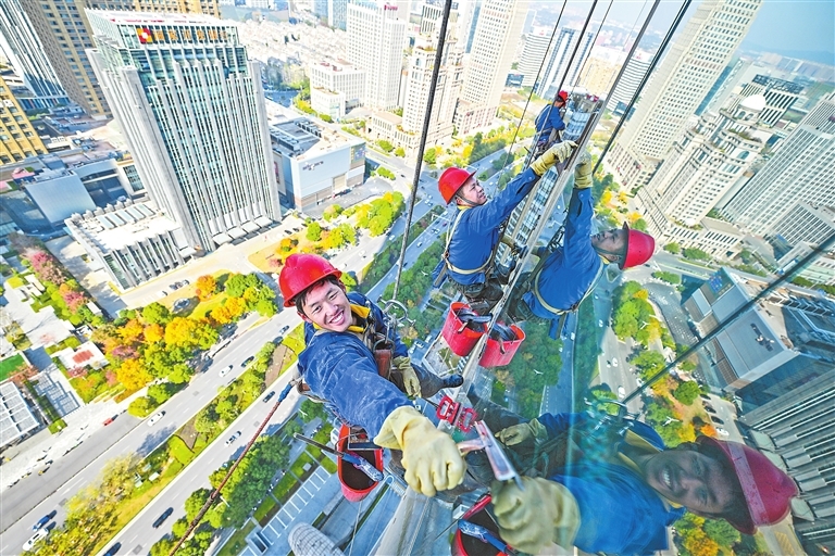 2024年12月15日中午，陈朝远（左）和工友毛泽宏（中）、童应颖对南昌市绿地双子塔玻璃幕墙进行清洗。
