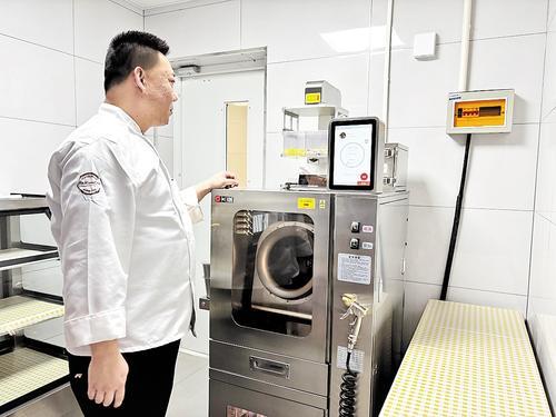 2024年12月25日，一位厨师正在后厨烹饪间，用炒菜机器人烹制菜品。 本报记者 李巍摄