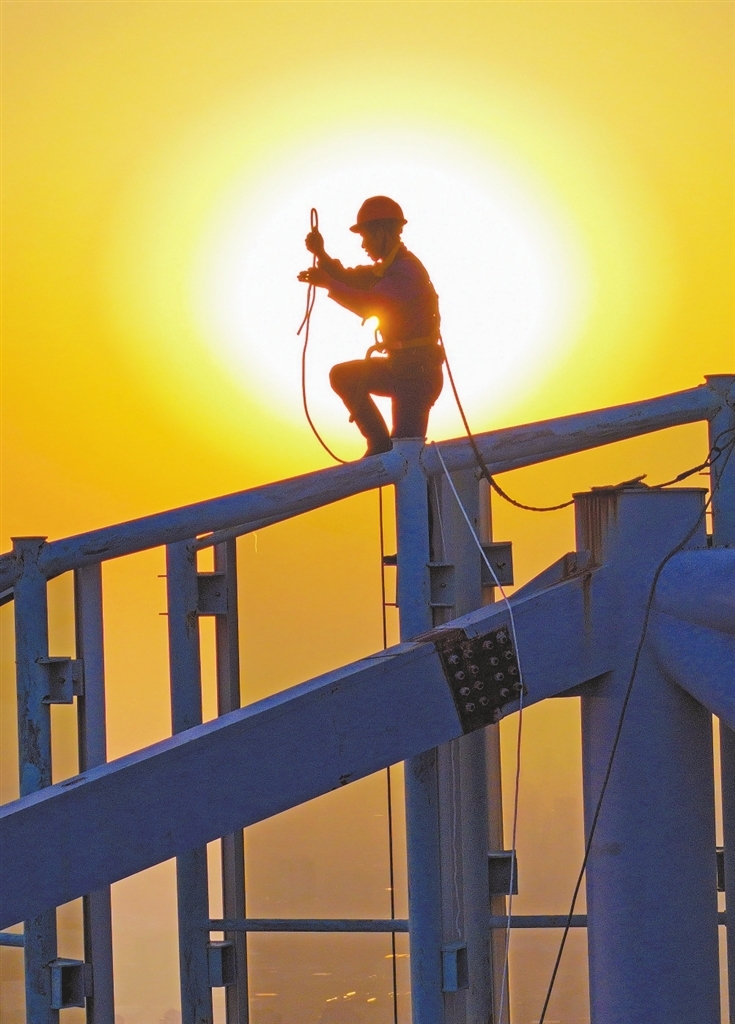 2024年12月15日傍晚，陈朝远在绿地双子塔A2楼顶的钢结构边缘作业。