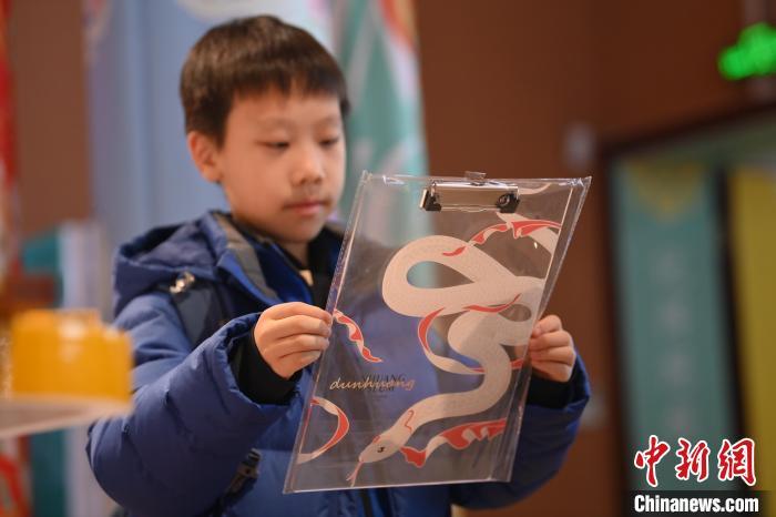 1月10日，在甘肃省敦煌市敦煌博物馆内，游客挑选“蛇”元素文创产品。随着农历乙巳蛇年临近，敦煌博物馆内具有敦煌文化的“蛇”元素文创产品渐热。中新社记者　李亚龙　摄