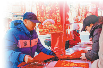 天津杨柳青古镇御河道年货大集上，一名顾客在选购年画。李慧敏摄