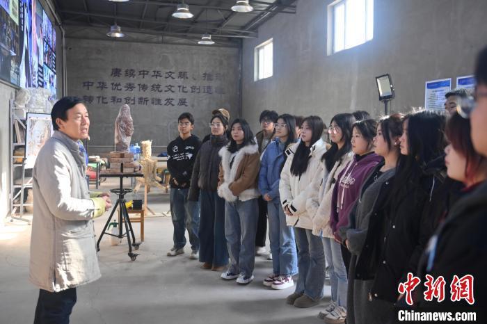 1月14日，甘肃省酒泉市，甘肃酒泉职业技术学院非物质文化遗产敦煌彩塑技艺传习所内，该校甘肃省级敦煌壁画技艺传承创新工作室负责人王权朝(左一)向学生们讲述敦煌文化。中新社记者　李亚龙　摄