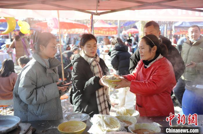 图为市民在洧川大集上品尝当地特色美食麻酱烩面。闫吉庆 摄