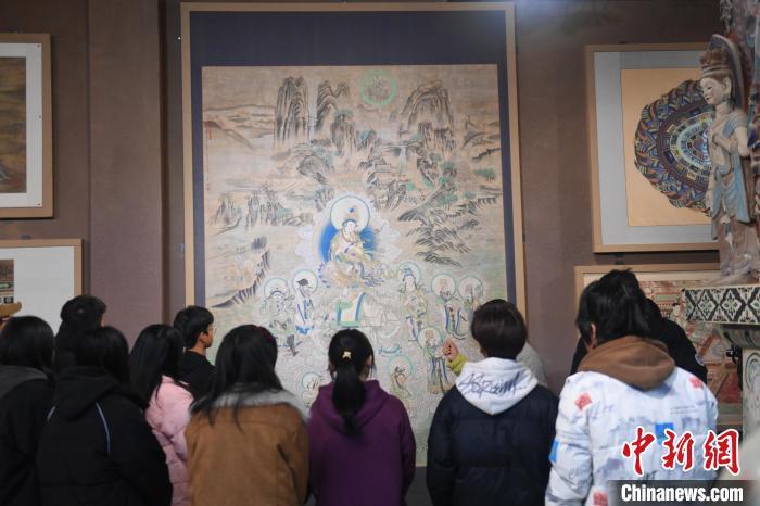 1月14日，甘肃省酒泉市，甘肃酒泉职业技术学院非物质文化遗产敦煌彩塑技艺传习所内，学生们参观敦煌壁画作品。中新社记者　李亚龙　摄