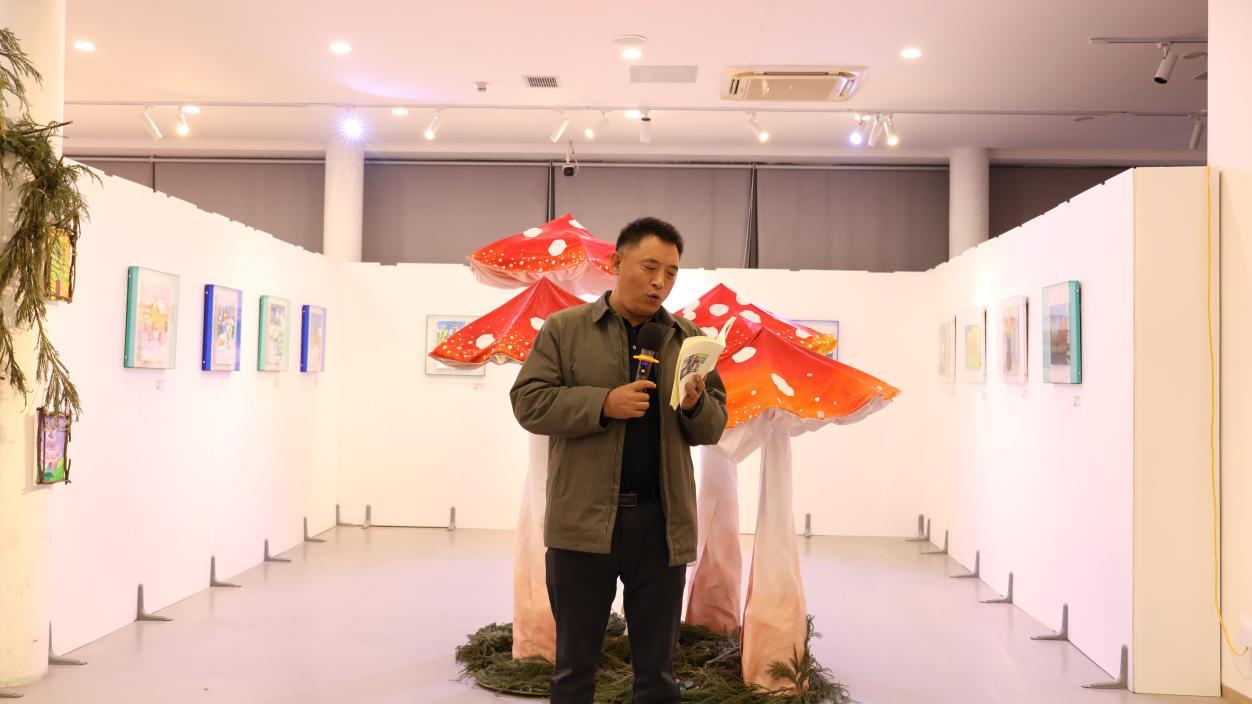 惠州诗人仲诗文在“第二届深港少儿美术作品展”展厅读诗。