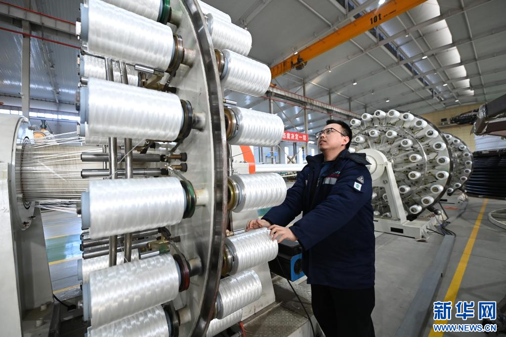 1月7日，在宝鸡天联汇通复合材料有限公司生产车间，工人为柔性复合高压输送连续管生产设备安装管道增强材料。