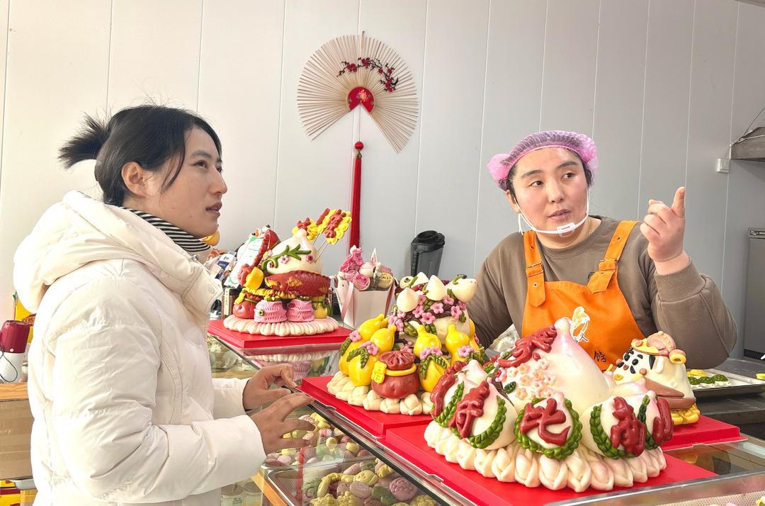 程雅娟（右）正在给顾客讲解花饽饽的款式